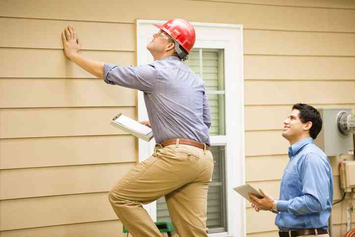 two men inspecting house wall