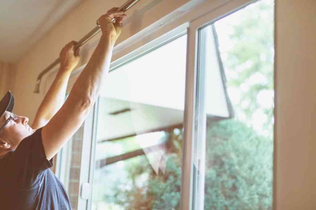 person installing bar for curtain